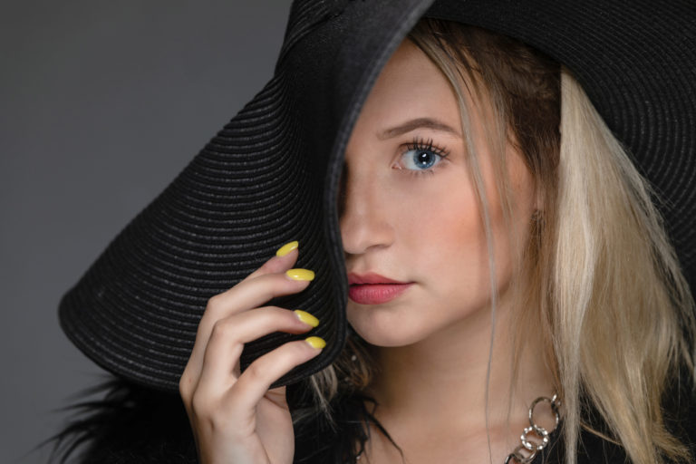 Close up photo of blonde girl with large black hat