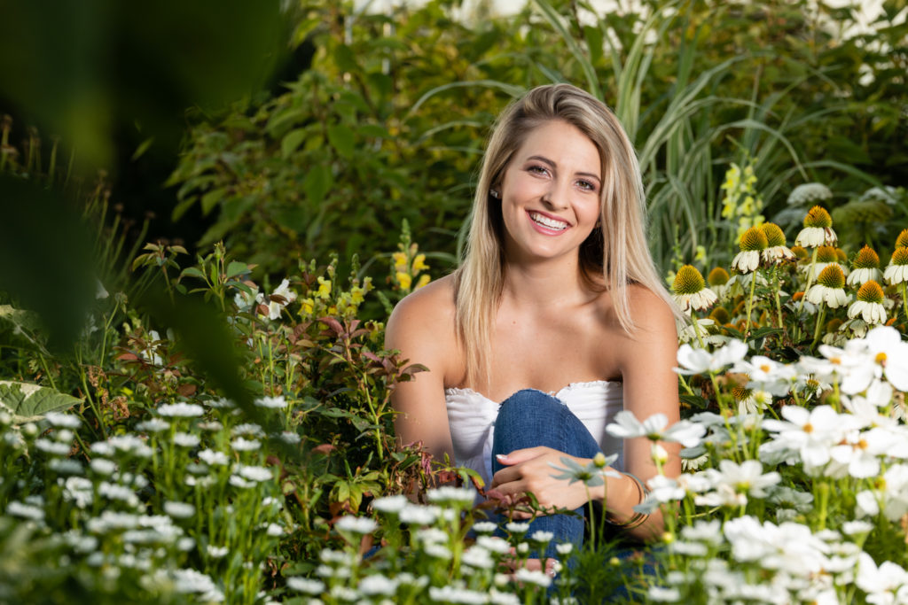 Young senior student sitting outdoor in field of flowers