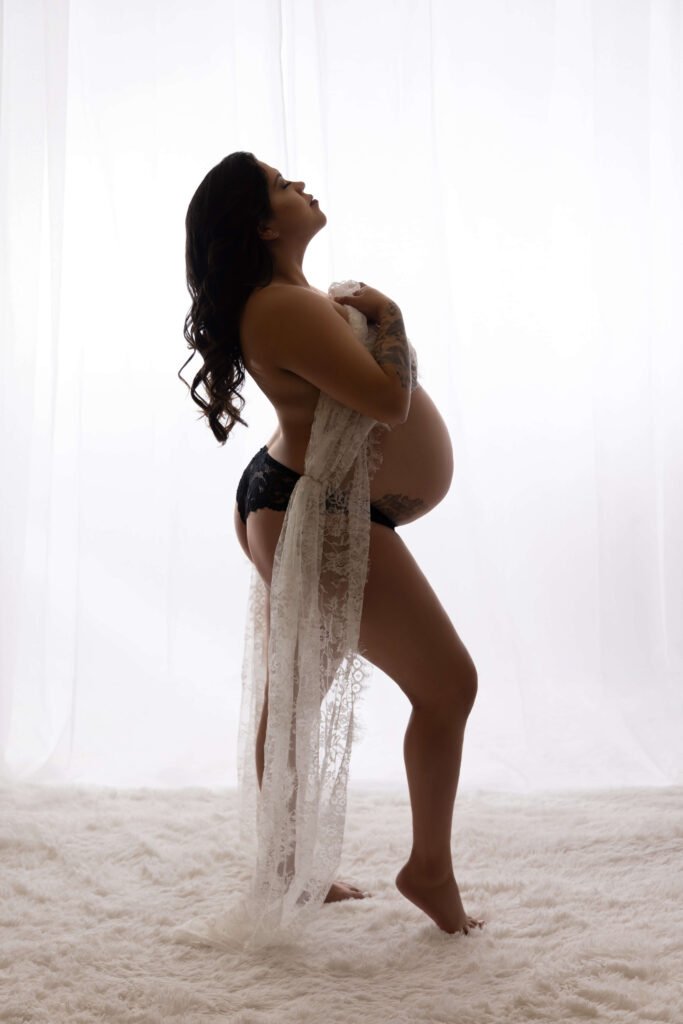 Pregnant woman in silhouette pose for boudoir photoshoot.