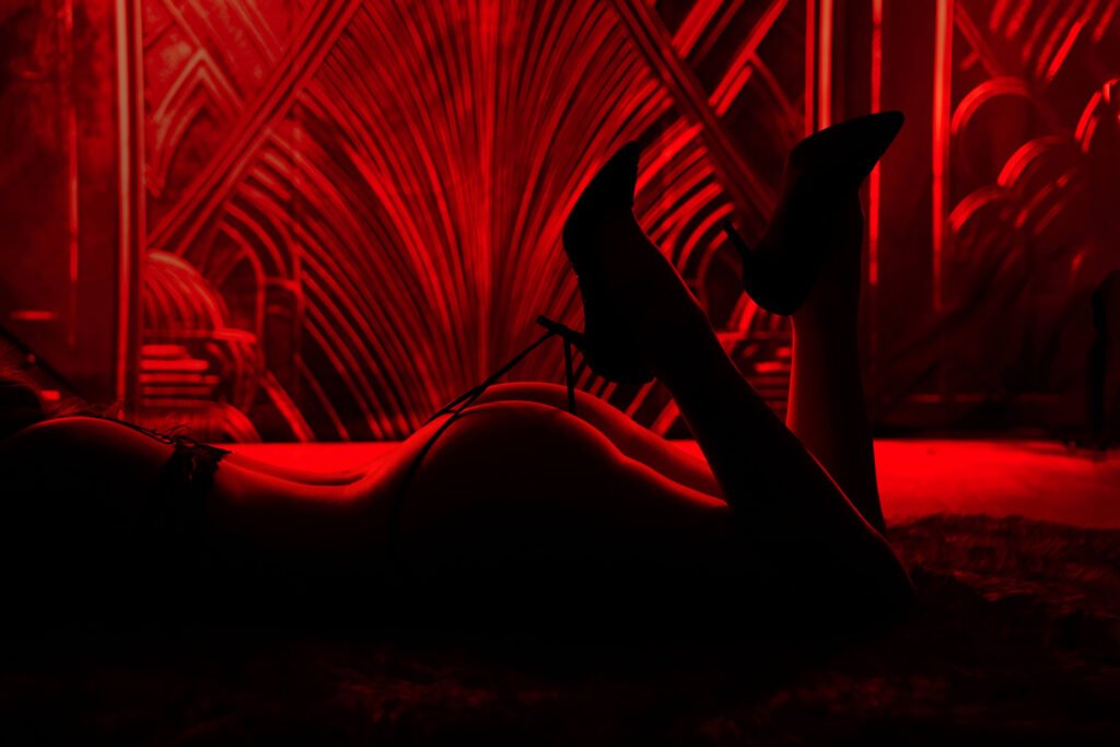 Woman's bosy under red light. The woman is wearing lingerie and heels. 